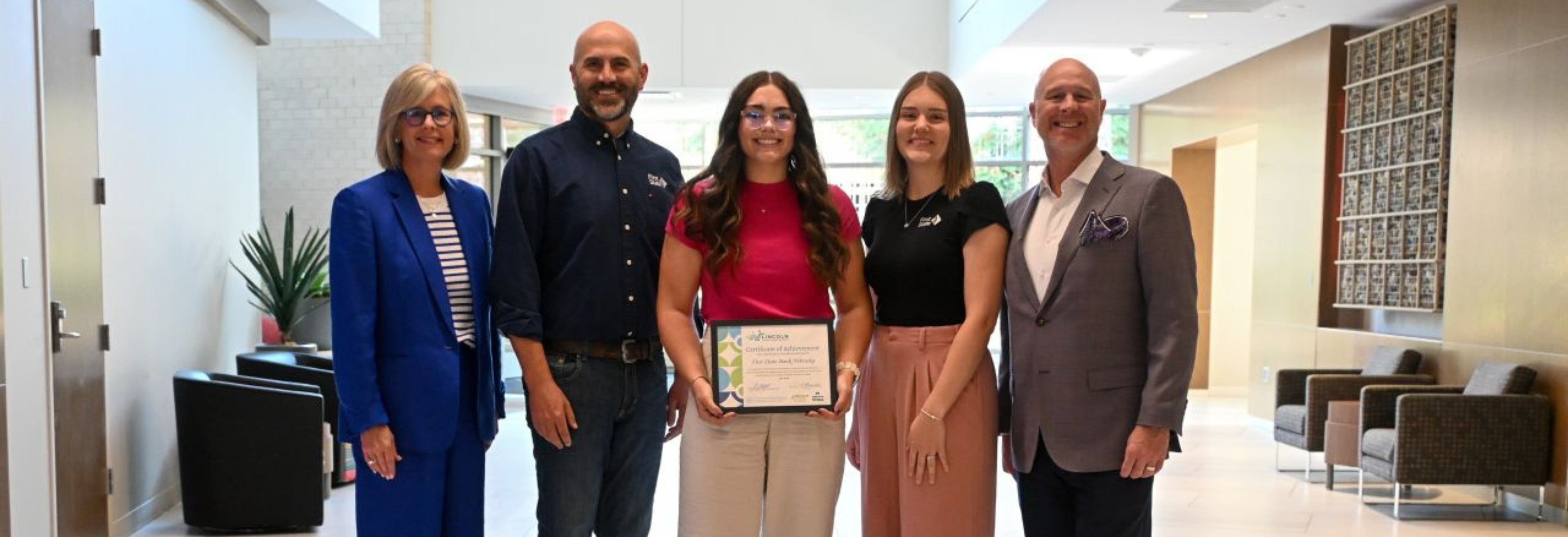 five people standing in a line holding a certificate