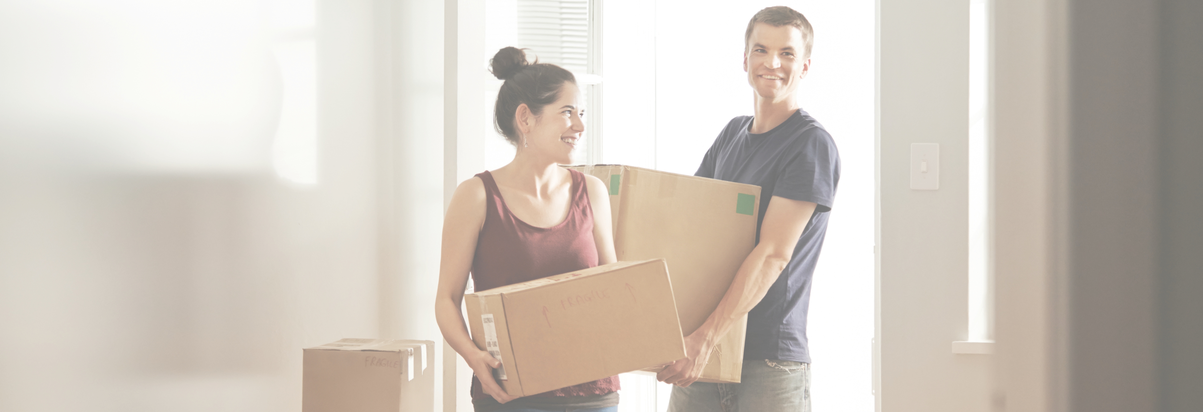 Young couple moving boxes into new home