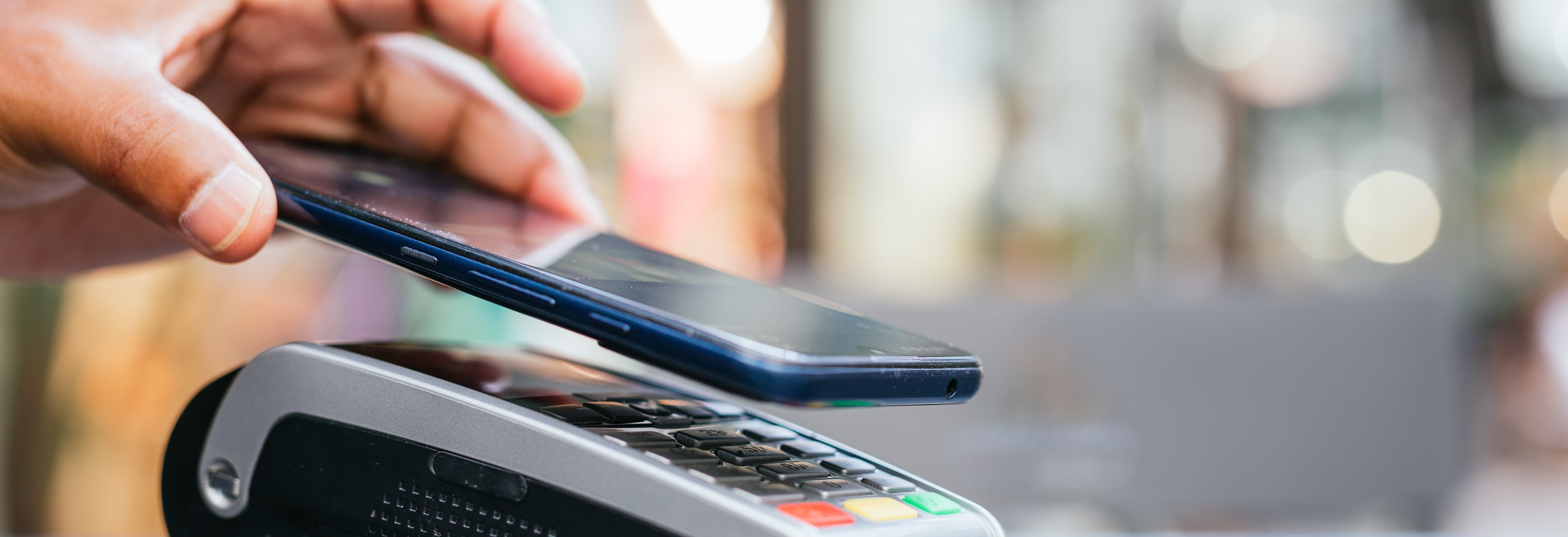 hand tapping a phone on a payment terminal