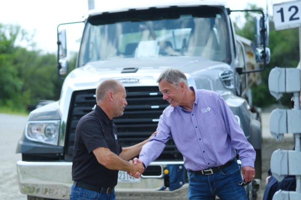 two men shaking hands in front of a semi truck