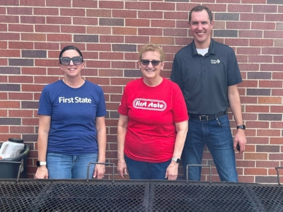 three people standing behind a large grill