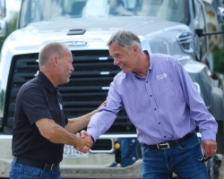 two men shaking hands in front of a semi truck