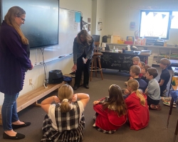 two women standing in a classroom teaching kids sitting on the floor